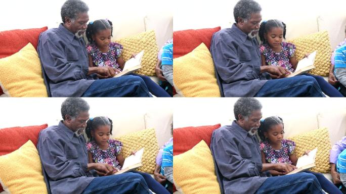 爷爷给沙发上的小女孩读书