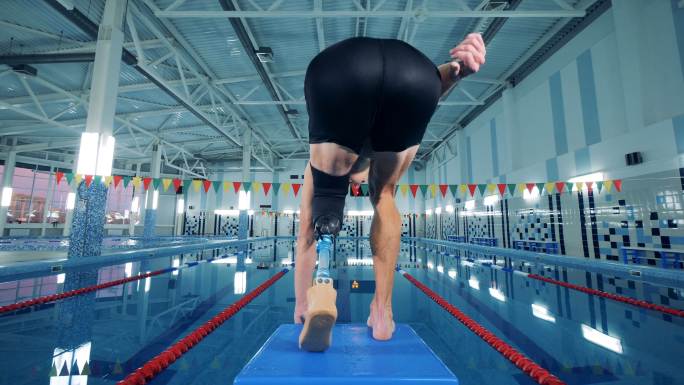 带假肢的专业游泳运动员跃入游泳池