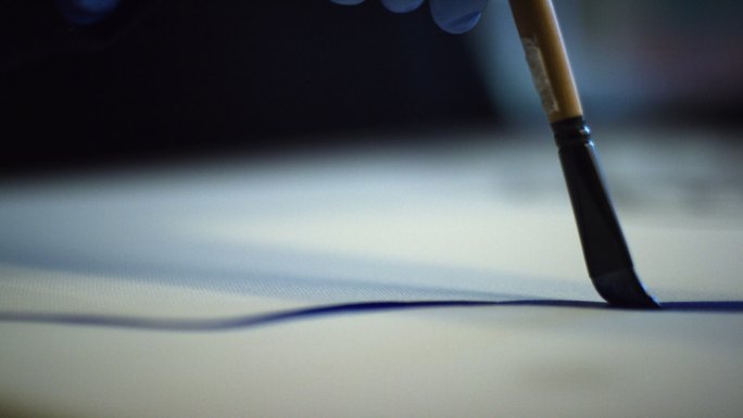 一个艺术家用画笔在画布上写字的特写镜头