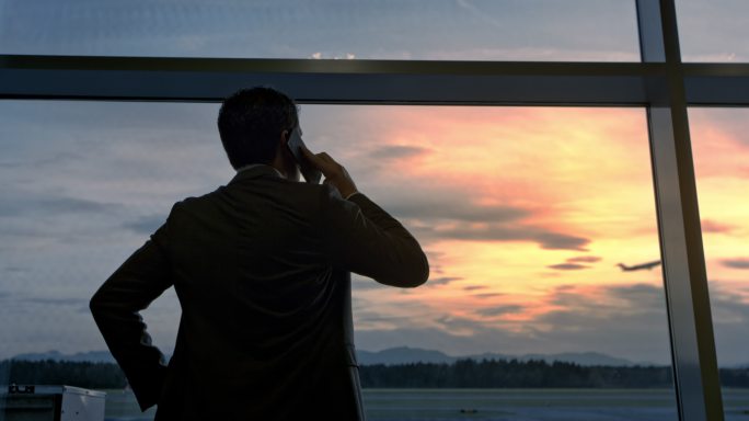 边打电话边透过机场的玻璃墙观察飞机起飞