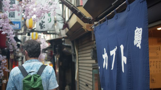 游客在东京烟雾弥漫的小巷中行走的后视图