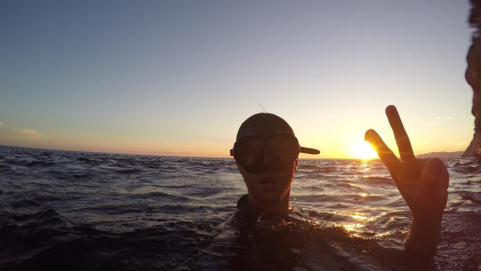 落日时分潜水员在水中做和平手势