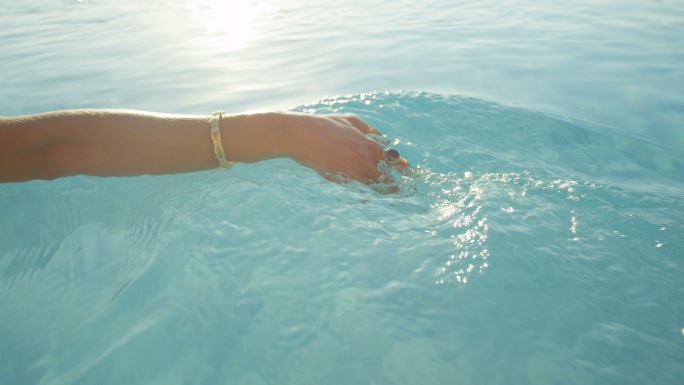 游泳池里，女人用手指在水面上滑动