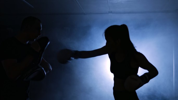 女子和教练在拳击俱乐部训练