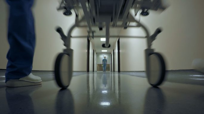 担架上的病人被运送走过医院走廊
