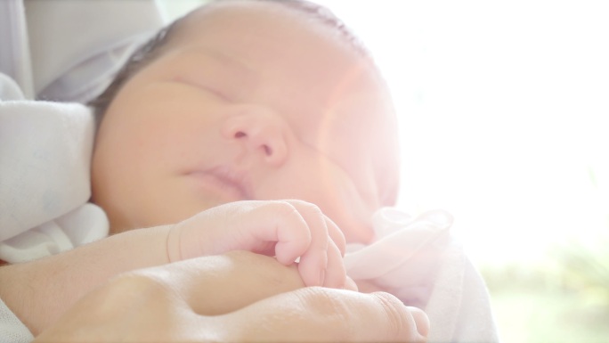 特写镜头父母的手抱着新生儿，婴儿