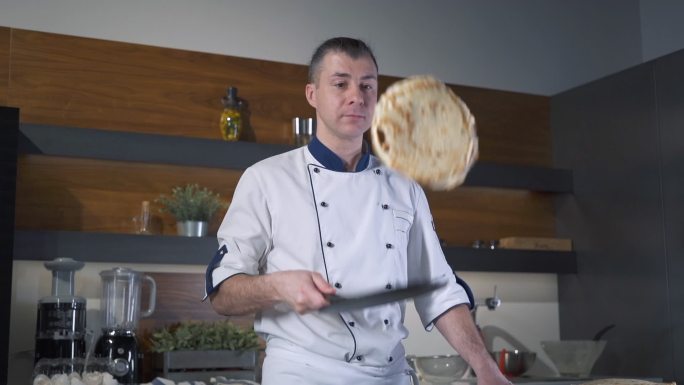 餐厅厨房里的专业厨师在锅里扔煎饼。