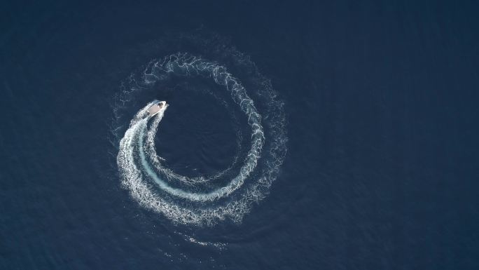 一条船在形成波浪的圆圈中行驶的鸟瞰图。