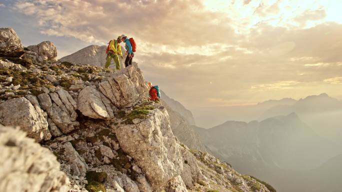 三个登山者在午后的阳光下到达山顶