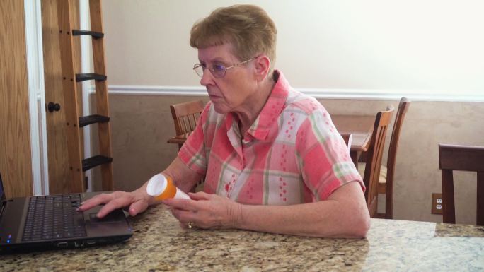 一位老年妇女在电脑上搜索处方药