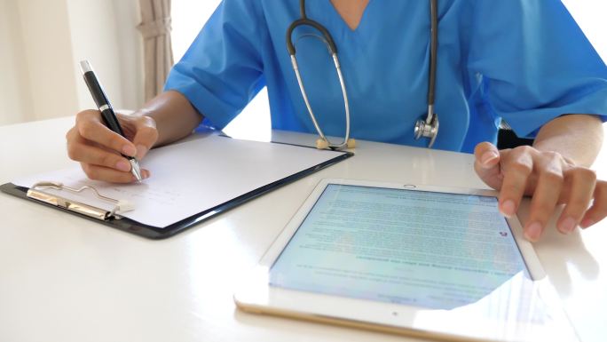 女医生在医学图表上书写并在平板电脑上分析