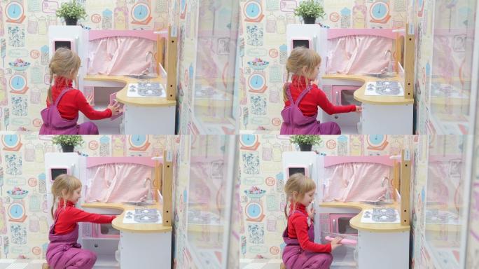 小女孩在玩带微波炉的玩具厨房
