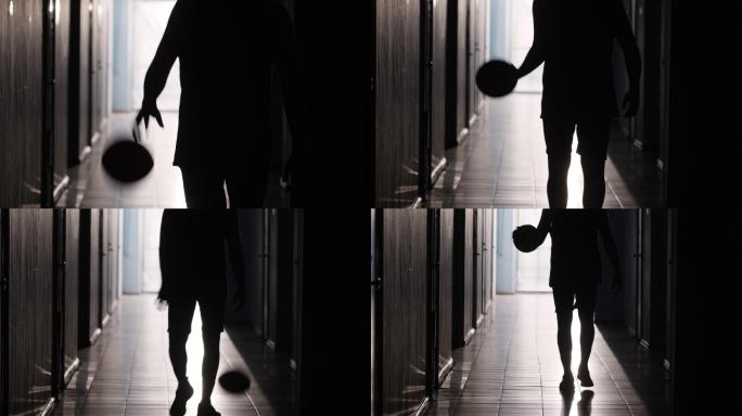 篮球运动员走在走廊里运球的剪影