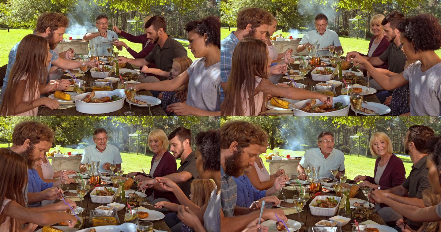 一个家庭坐在餐桌旁野餐，享受烤肉的食物。