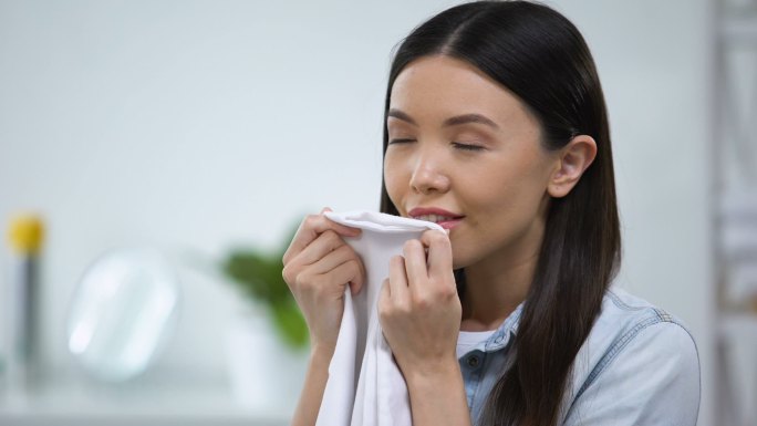 女性闻着新鲜的亚麻布微笑着