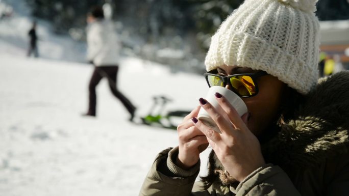 在雪地里喝咖啡的女人