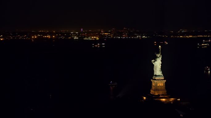 空中的自由女神像在夜晚闪耀在纽约港