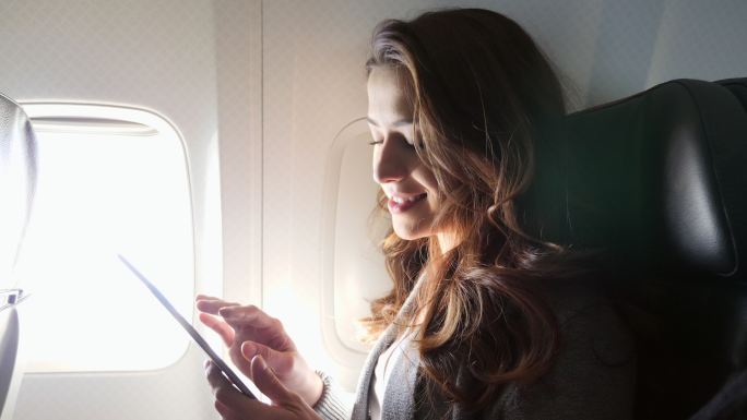 微笑的年轻女子在飞行中使用智能手机
