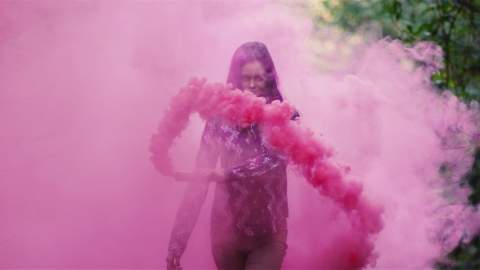 女孩拿着一枚粉红色的烟雾弹挥手