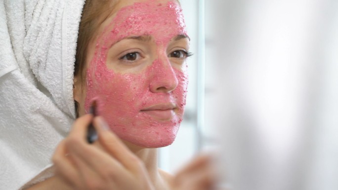 年轻女子在脸上敷上粉色保湿面膜