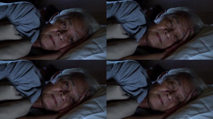一个沮丧的老人躺在床上失眠睡不着觉