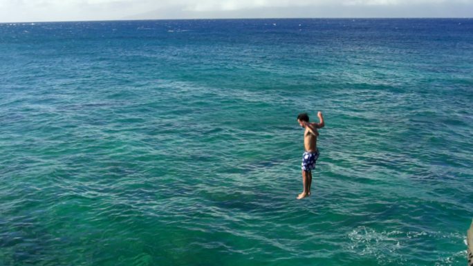 跳入海里的男人海边跳水焦石岩石洗澡潜泳