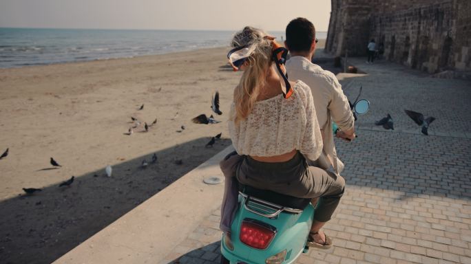 在海边骑电瓶车的情侣