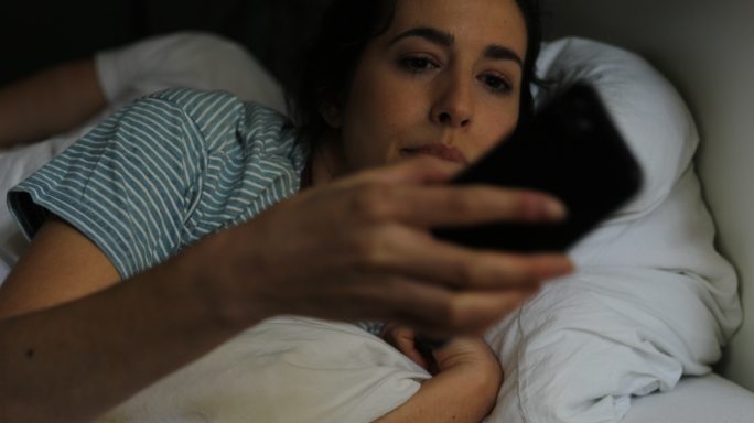 女性睡醒后使用智能手机