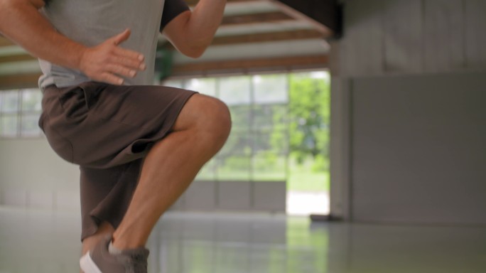 男子在健身运动锻炼期间做高膝盖跳跃运动。