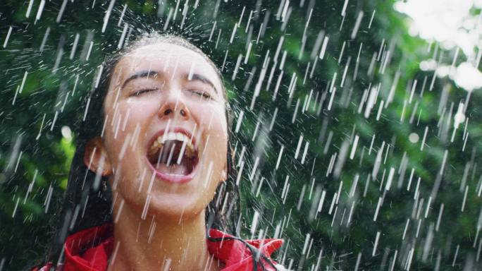 一个年轻女人穿着防护斗篷在雨中自由自在