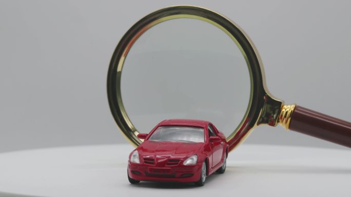 一辆红色小汽车在放大镜前旋转