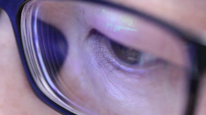 戴眼镜的人眼睛特写眼镜上反射的电脑编码