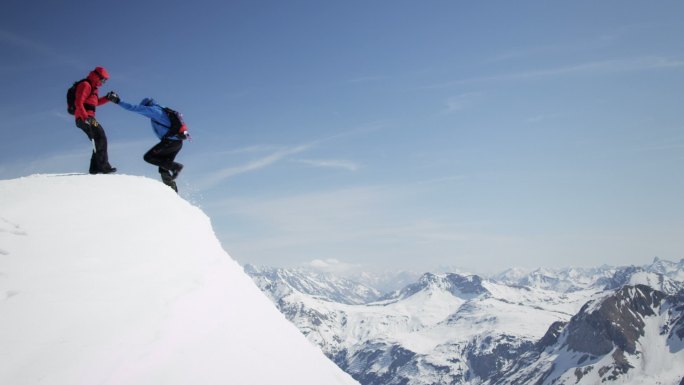登山者互相帮助到达白雪覆盖的山峰
