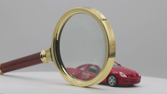 一辆红色汽车在魔方下面、放大镜前面旋转