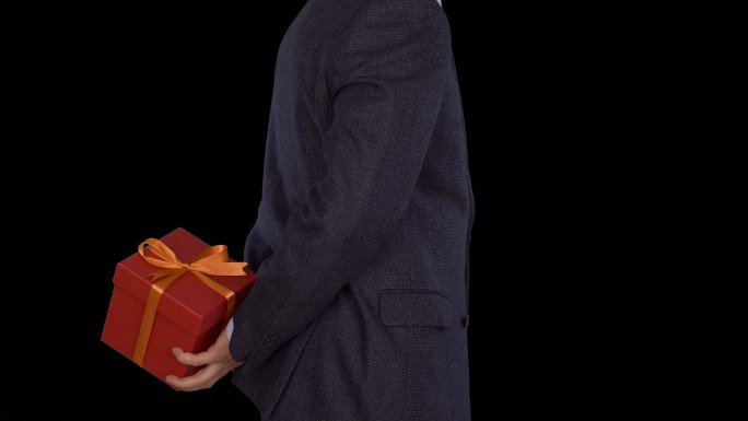 一个穿西装的男人从背后拿出红色的礼盒。