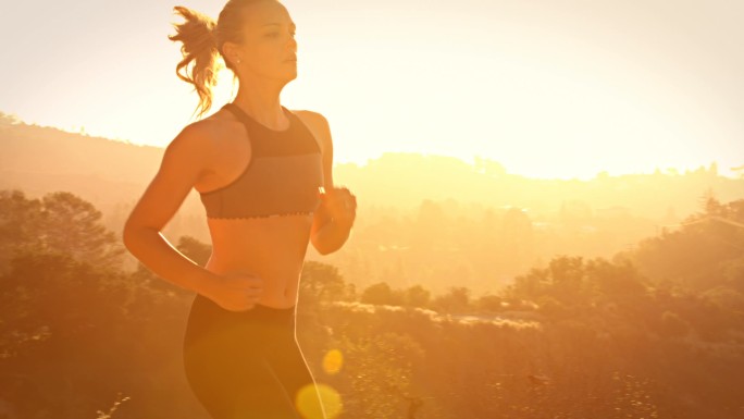 健身女子慢跑迎着光跑有氧运动增强体魄