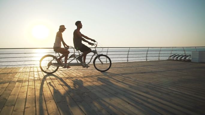 一对夫妇在海边骑双人自行车