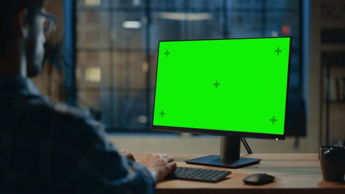 在使用绿色屏幕电脑工作的男人