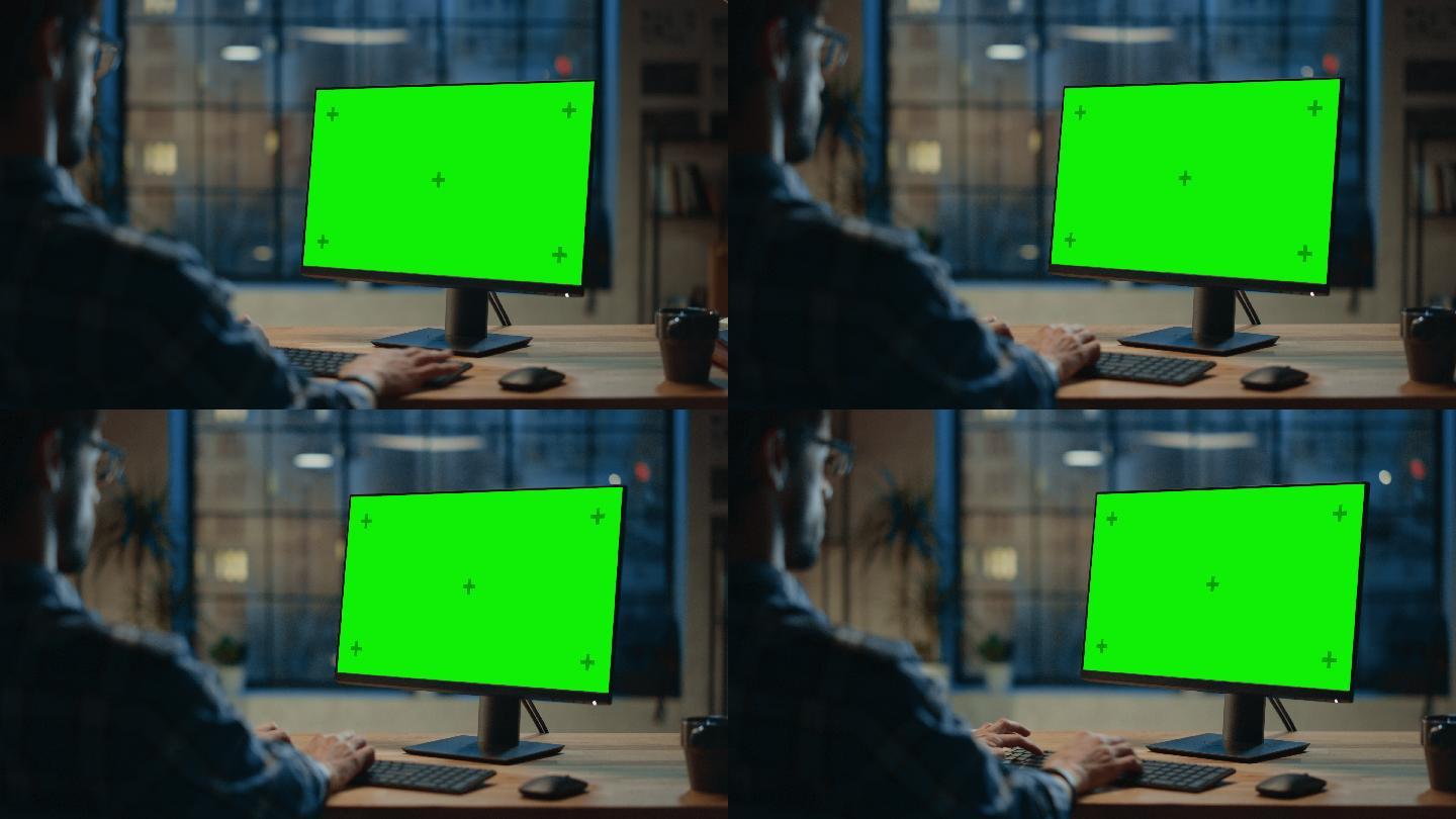 在使用绿色屏幕电脑工作的男人