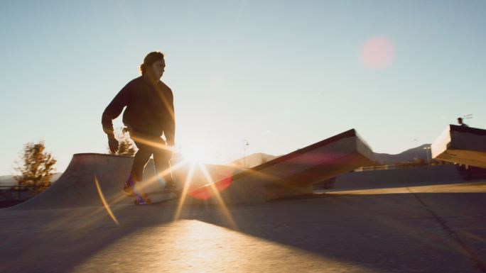 滑板表演青少年夕阳下滑滑板滑板公园极限运