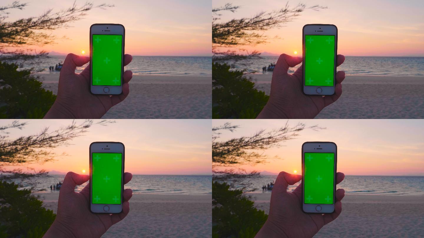 在沙滩上用绿屏手机拍照的人