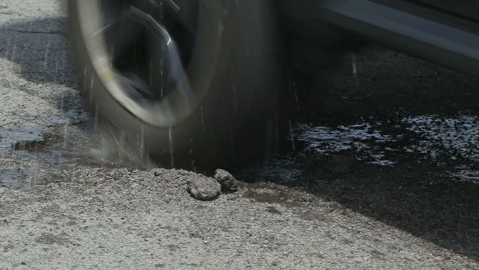 行驶过水坑的汽车路面水坑水泥路破裂