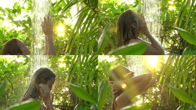 年轻苗条的女人在热带花园里享受清爽的淋浴