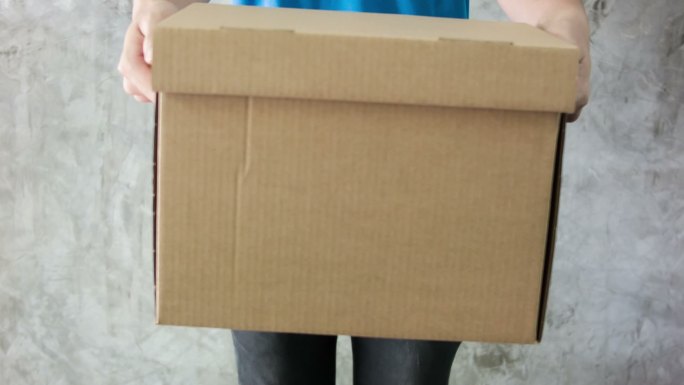 送货员拿着一个纸板箱。
