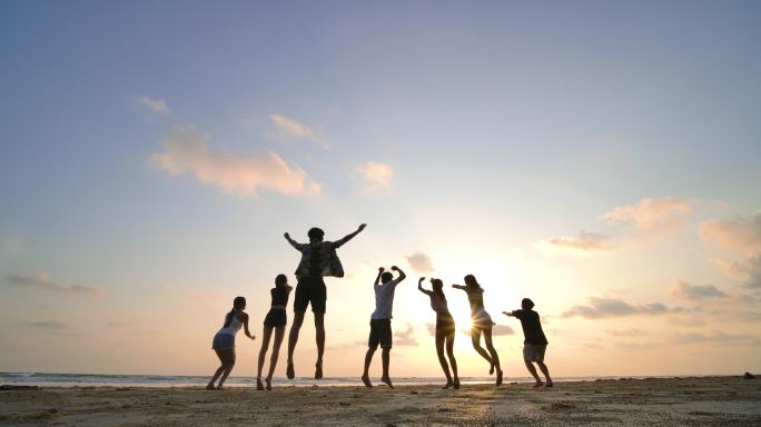 日落时分，朋友们在沙滩上跳起的剪影