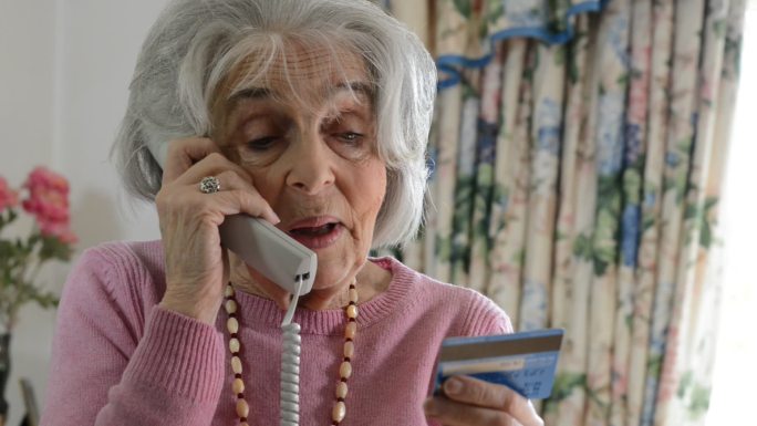 老妇人在电话里读信用卡的卡号