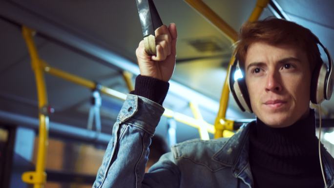 在公共汽车上听音乐的时髦男人