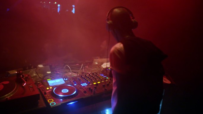 在派对上戴着耳机的DJ旋转音乐。