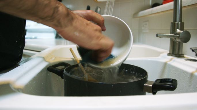一个人的手打开水龙头洗碗