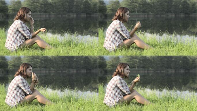 坐在草地上闻薄荷叶的年轻女子